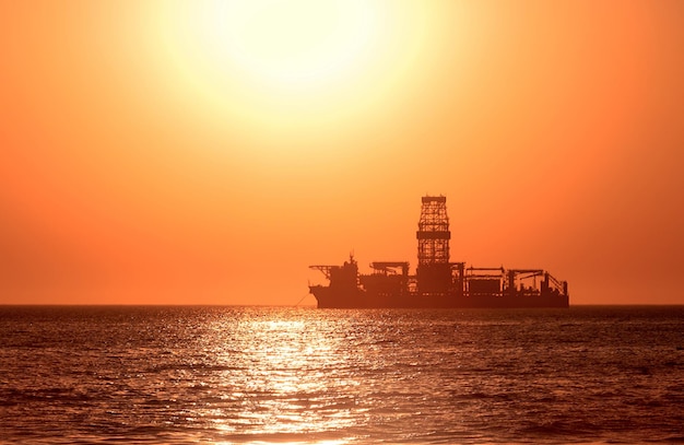 Ein großes Schiff am Horizont im Atlantik unter der hellen Sonne und dem roten Sonnenuntergang Sonnenlichtreflexion aus dem Wasser