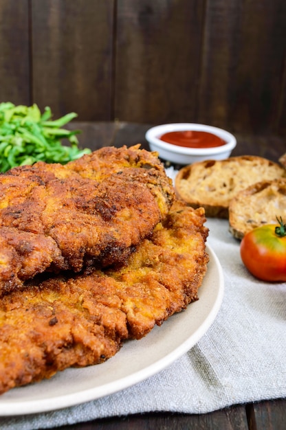 Ein großes Wiener Schnitzel auf dunklem Holztisch