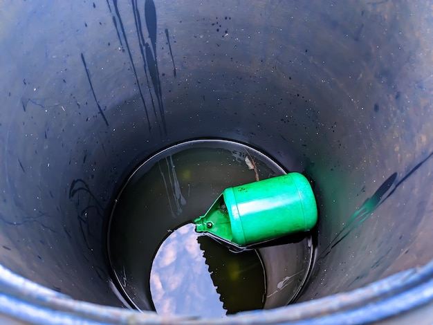 Ein grüner Behälter, der sich in einem blauen Fass mit Wasser befindet