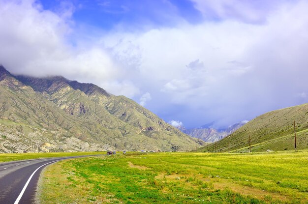 Ein grünes Bergtal, umgeben von Felsen unter blauen Wolken Sibirien Russland