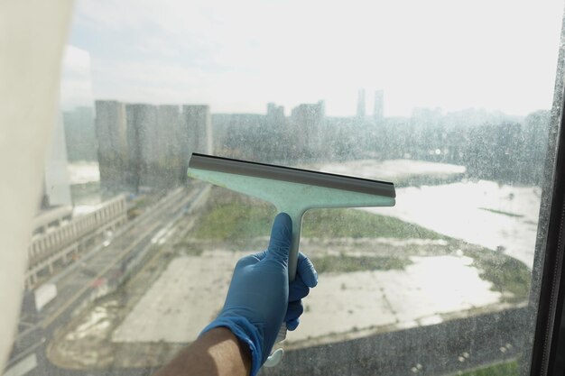 Foto ein gummi-squeegee reinigt ein seifiges fenster