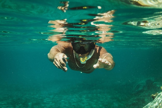 Ein gutaussehender mann hat spaß in den sommerferien und erkundet den meeresboden beim tauchen im meer.