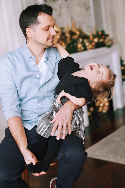 Foto ein gutaussehender mann spielt mit seiner lustigen tochter nahe dem weihnachtsbaum zu hause