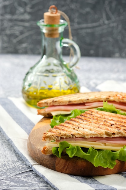 Ein halbes Sandwich in Form eines Dreiecks auf einem Holzbrett. Das Sandwich ist mit einem Salatblatt und Kirschtomaten dekoriert.