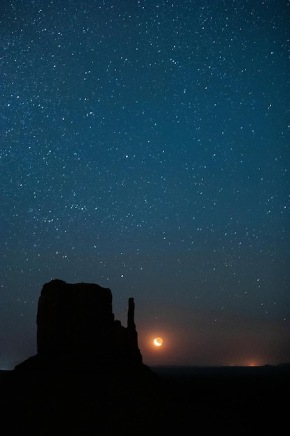 Foto ein halbmond erhebt sich über dem talboden im monument valley