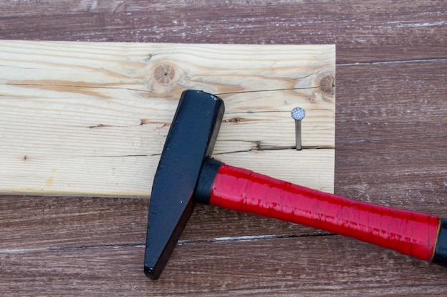 Foto ein hammer legt sich auf ein stück holz mit einem nagel darauf.