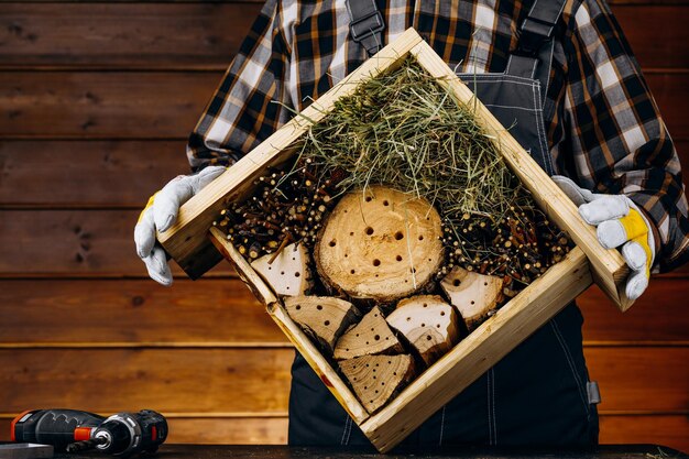 Ein Handwerker, der ein Holzhaus für Insekten herstellt Ein Zimmermann, der in der Werkstatt ein Werkzeug verwendet