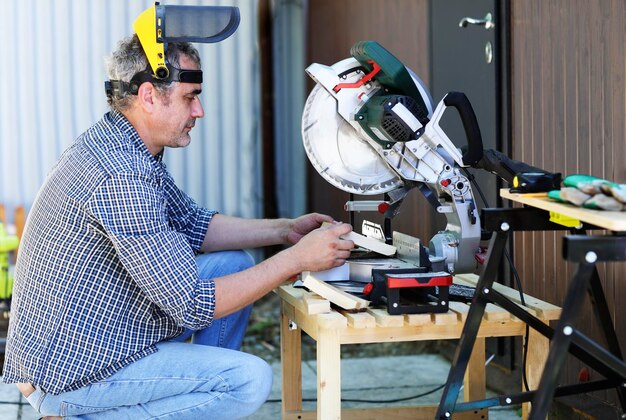 Ein Handwerker mit Schutzhelm arbeitet mit einer Gehrungssäge