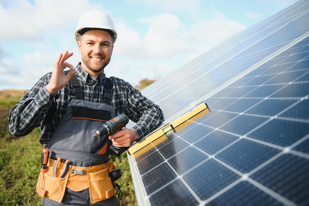 Ein Handwerker steht mit Sonnenkollektoren auf dem Dach und lächelt in die Kamera