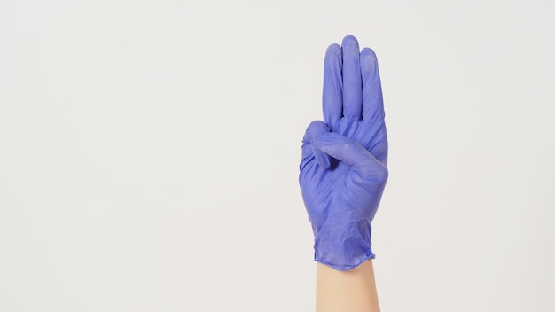 Ein Handzeichen von 3 Fingern zeigt nach oben, was drei Drittel bedeutet oder als Protest verwendet wird. Tragen Sie einen violetten Latexhandschuh