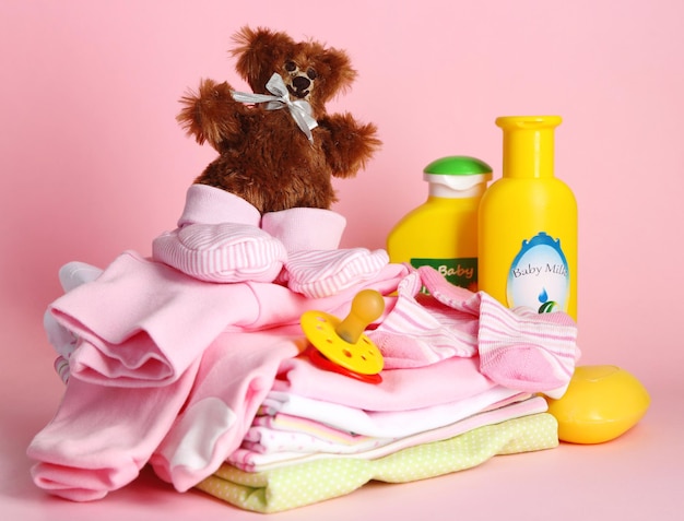 Ein Haufen Babykleidung auf rosa Hintergrund