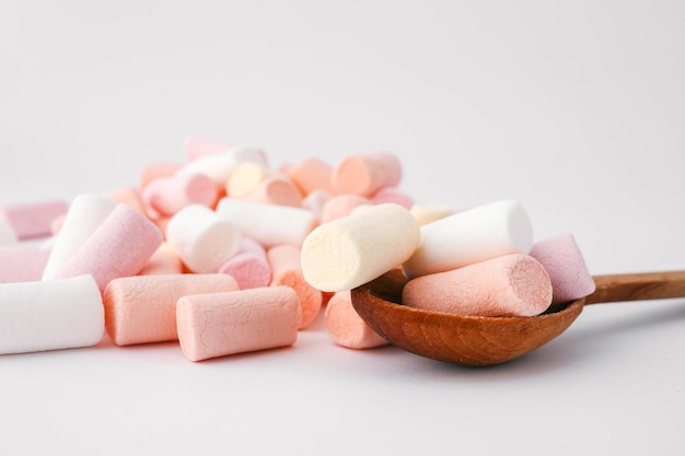 Ein Haufen farbenfroher Marshmallows in weichen Pastellfarben von rosa, weiß und gelb auf einem einfachen weißen Hintergrund perfekt für Themen von Süßigkeiten und minimalistischem Design