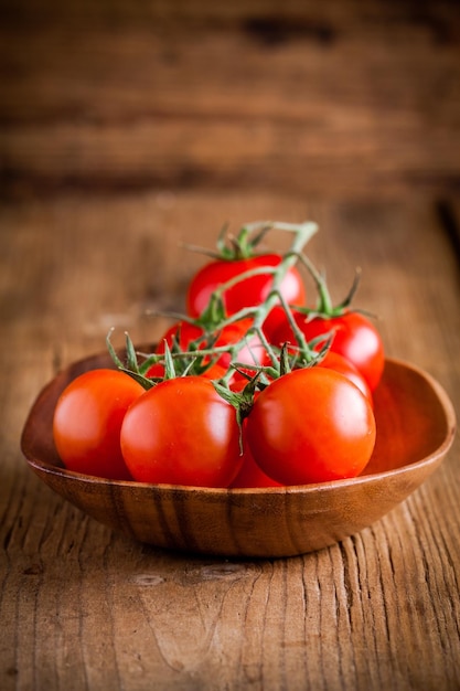 Ein Haufen frischer Bio-Kirschtomaten in einer Schüssel auf rustikalem Holzhintergrund