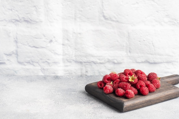 Ein Haufen frischer saftiger Himbeeren auf einem Holzbrett