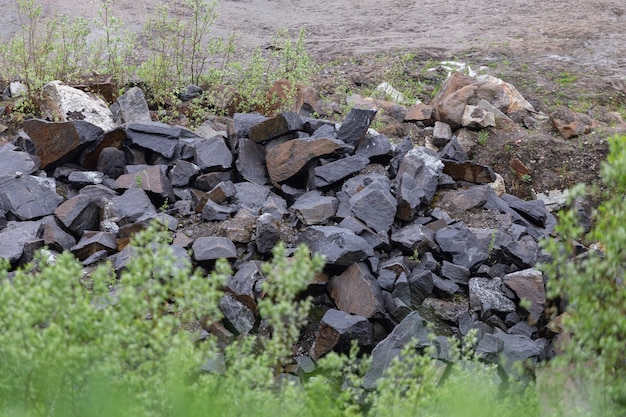 Ein Haufen großer Steine wird in der Nähe der Straße in der Nähe des Waldes abgeladen