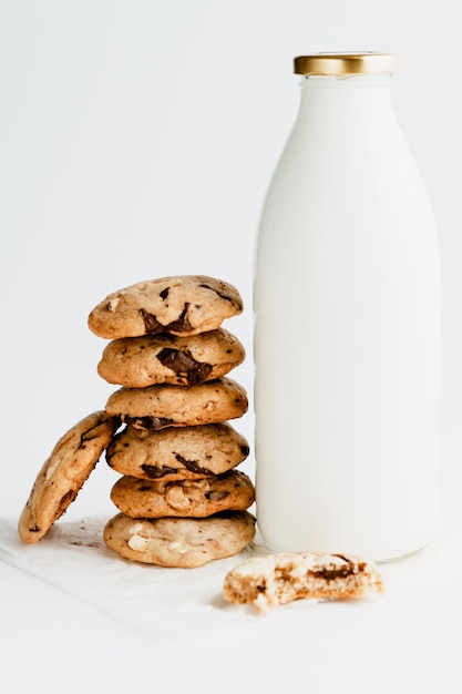 Ein Haufen hausgemachter Kekse mit Schokoladenstückchen neben einer Flasche Milch