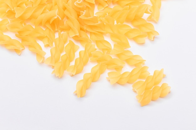 Ein Haufen ungekochter Fusilli-Nudeln auf einem weißen Tisch verstreut