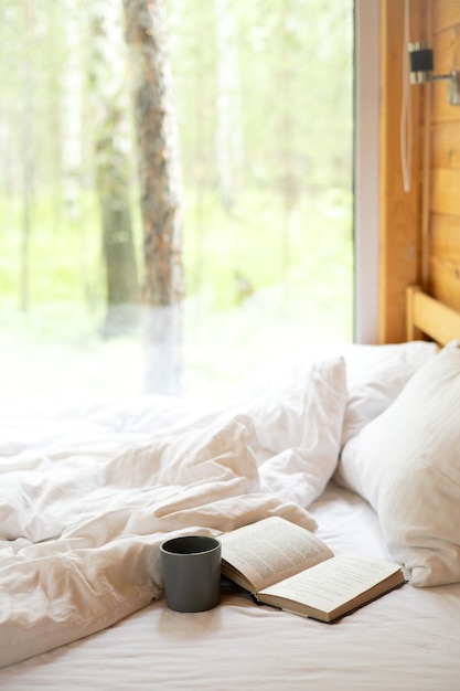 Ein Haus mit Fensterblick auf den Wald Erholung im Freien Ein Buch und eine Tasse stehen auf dem Bett Morgendliche Glamping-Meditation Allein mit der Natur