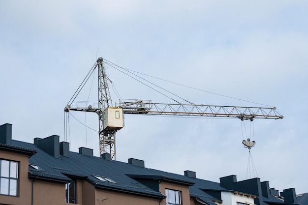 Ein Haus mit schwarzem Dach, im Hintergrund ein Baukran. Wohnungsbau