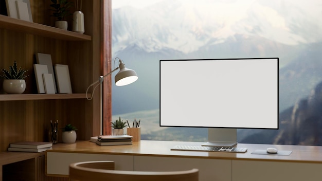 Ein Heimbüro verfügt über ein Computer-Mockup gegen das Fenster mit Blick auf schneebedeckte Berge