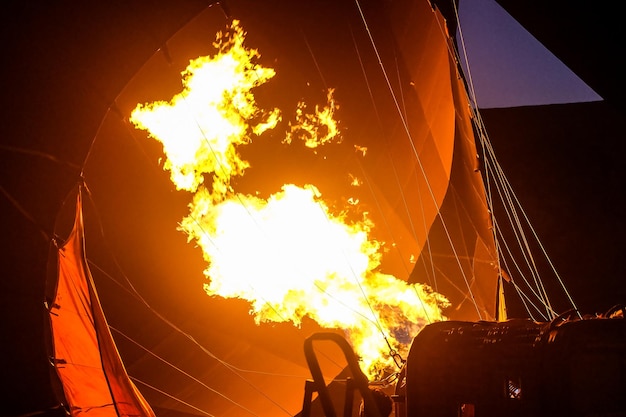 Ein Heißluftballon, der vor Sonnenaufgang heiße Luft mit Flammen gefüllt ist