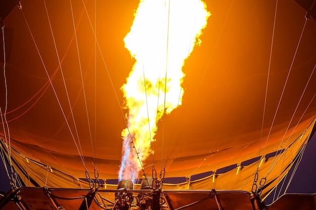 Ein Heißluftballon, der vor Sonnenaufgang heiße Luft mit Flammen gefüllt ist