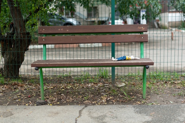 Ein heller Spielzeughase liegt auf einer Holzbank auf dem Spielplatz, die ein Kind hinterlassen hat