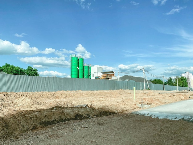 Ein hellgrüner Betonknoten steht hinter einer Bauzaunproduktion aus Beton