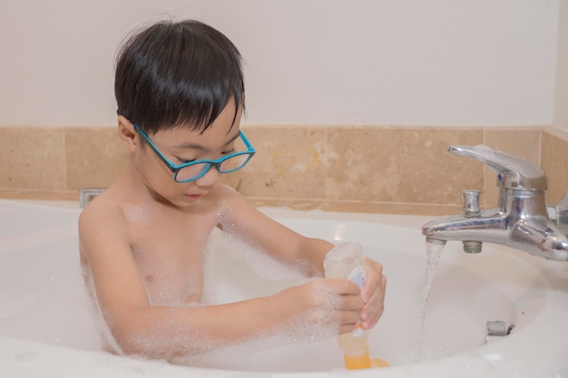 Ein hemdloser Junge badet zu Hause in einer Badewanne