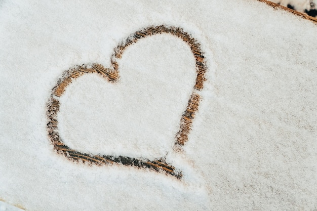 Ein Herz mit dem Finger auf den Schnee gezeichnet