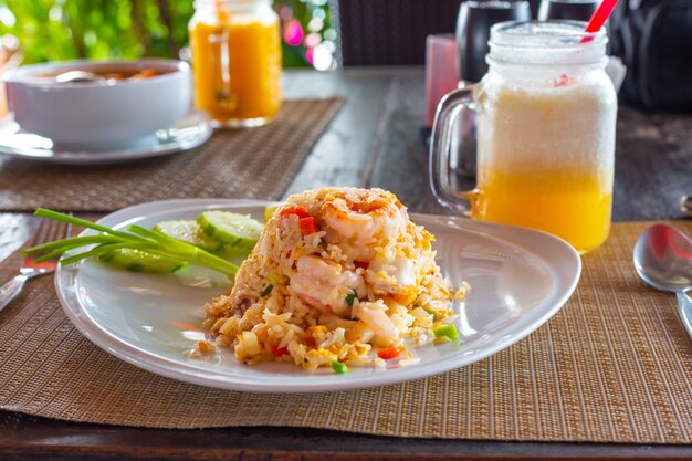 Ein herzhafter köstlicher Outdoor-Lunch-Reis mit Meeresfrüchten und Gemüse auf einem weißen Teller und exotischen Früchten