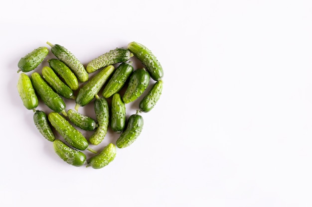 Ein Herzsymbol aus kleinen frischen grünen Gurken mit Platz für Text auf weißem Hintergrund