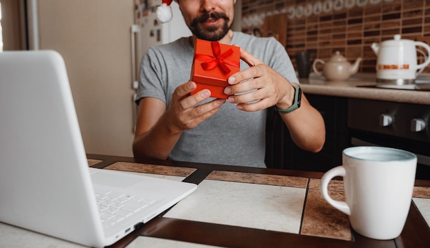 Ein Hipster-Mann mit einer roten Tasse, der zur Weihnachtszeit zu Hause sitzt