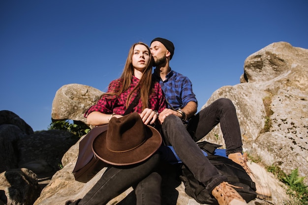 Ein Hipster-Reisepaar, das zusammen auf den Felsen in den Bergen sitzt