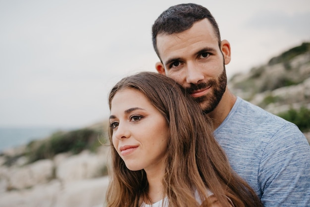 Ein hispanischer Mann umarmt ein Latina-Mädchen an der felsigen Meeresküste in Spanien