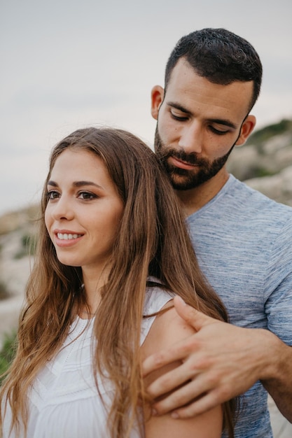 Ein hispanischer Mann umarmt ein Latina-Mädchen an der felsigen Meeresküste in Spanien