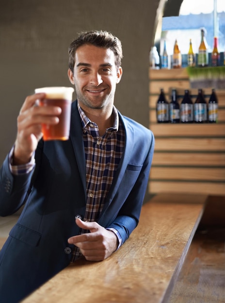 Ein Hoch auf Sie Aufnahme eines gutaussehenden jungen Mannes, der ein Bier an der Bar genießt