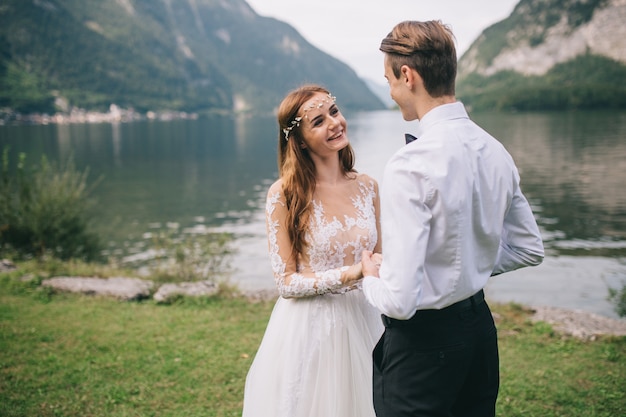 Ein Hochzeitspaar auf dem Hintergrundsee und den Bergen in der Märchenstadt von Österreich