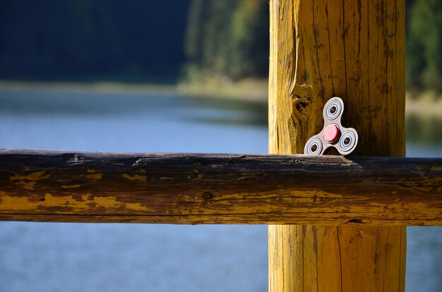 Ein hölzerner Spinner liegt auf einer hölzernen Stange gegen einen Hintergrund des Flusswassers