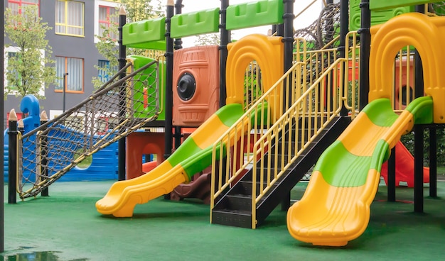 Ein Hof von Hochhäusern mit einem neuen modernen bunten und großen Spielplatz an einem regnerischen Sommertag ohne Menschen. Leerer Spielplatz im Freien. Ein Ort für Kinderspiele und Sport.