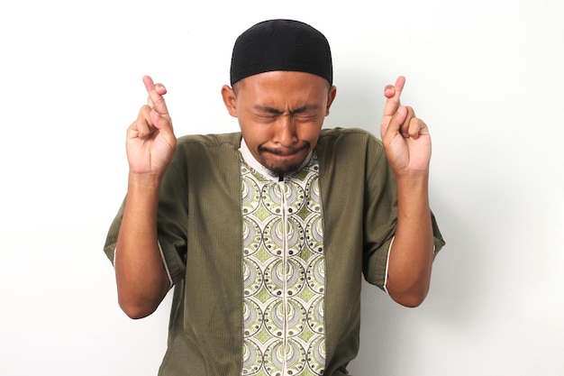 Ein hoffnungsvoller indonesischer muslimischer Mann kreuzte die Finger