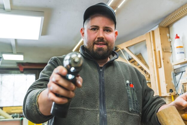 Foto ein holzarbeiter richtet einen bohrer auf die kamera