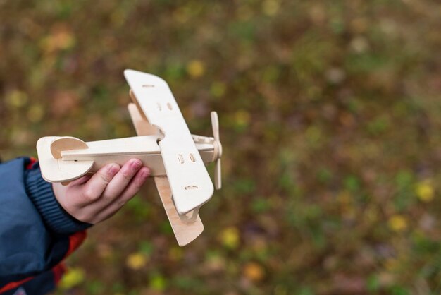 Ein Holzflugzeug in den Händen eines Kindes