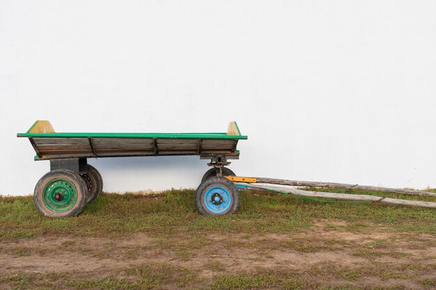 Ein Holzkarren mit Rädern von einem Auto an der weißen Wand der Scheune