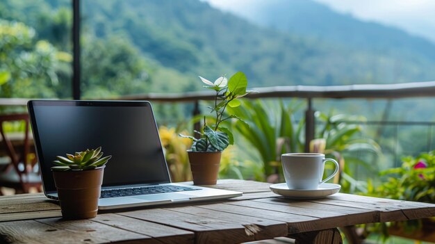 Ein Holztisch mit einem Laptop, einer Tasse Kaffee und einer Topfpflanze darauf Der Tisch befindet sich auf einem Balkon mit