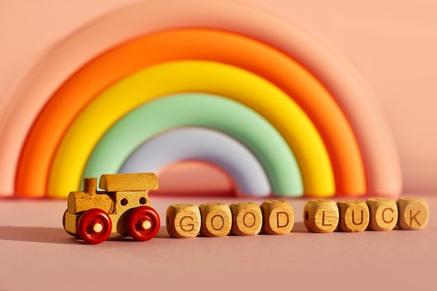Ein Holzzug mit Würfeln mit der Aufschrift viel Glück auf dem Hintergrund eines voluminösen hellen Regenbogens