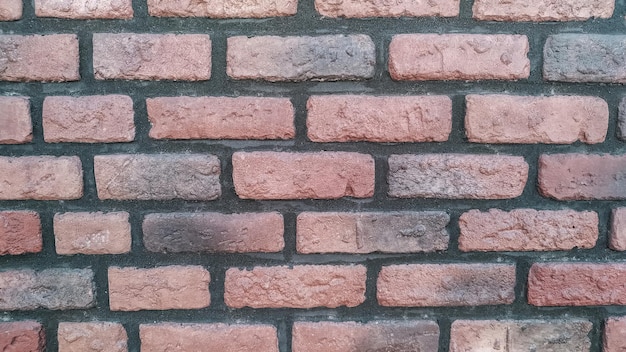 Ein horizontaler Abschnitt einer alten, schwarz-rot gestrichenen Backsteinmauer