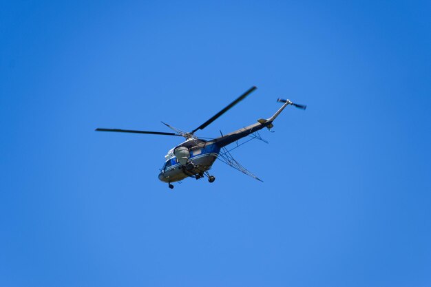 Ein Hubschrauber der landwirtschaftlichen Luftfahrt fliegt am blauen Himmel