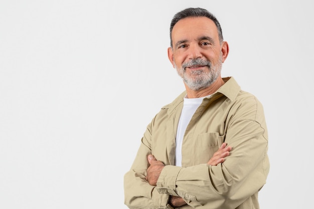 Ein hübscher älterer Mann posiert mit gefalteten Armen vor einem weißen Studio-Hintergrund