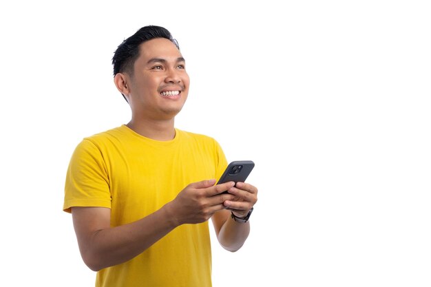 Ein hübscher asiatischer Mann benutzt ein Smartphone und schaut auf, während er lächelt, isoliert auf weißem Hintergrund